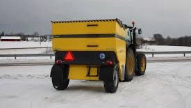 Rød traktor med slåmaskin står på en eng med nyslått gress en solrik dag.