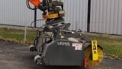 Rød traktor med slåmaskin står på en eng med nyslått gress en solrik dag.