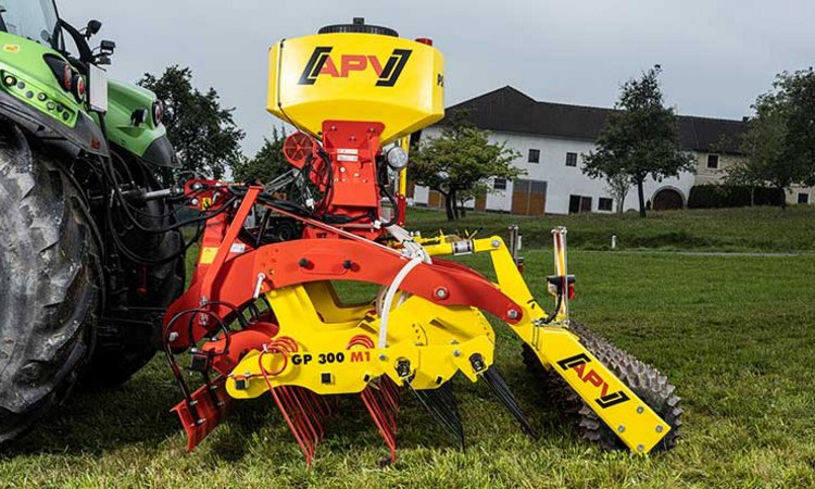 Rød traktor med slåmaskin står på en eng med nyslått gress en solrik dag.