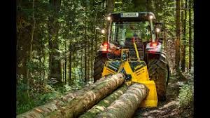 Rød traktor med slåmaskin står på en eng med nyslått gress en solrik dag.