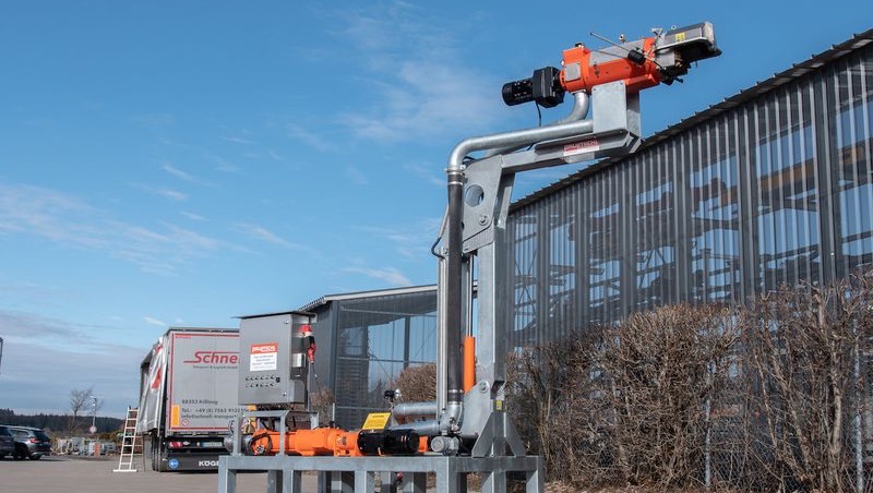 Rød traktor med slåmaskin står på en eng med nyslått gress en solrik dag.