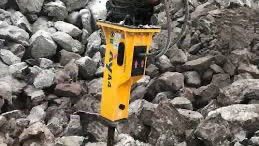 Rød traktor med slåmaskin står på en eng med nyslått gress en solrik dag.