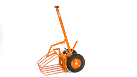 Rød traktor med slåmaskin står på en eng med nyslått gress en solrik dag.