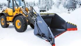 Rød traktor med slåmaskin står på en eng med nyslått gress en solrik dag.
