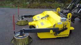 Rød traktor med slåmaskin står på en eng med nyslått gress en solrik dag.